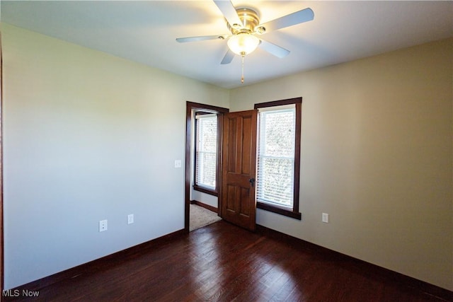 empty room with baseboards, a ceiling fan, and dark wood-style floors