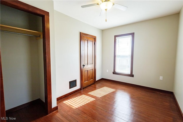 unfurnished bedroom with ceiling fan, baseboards, visible vents, and wood finished floors