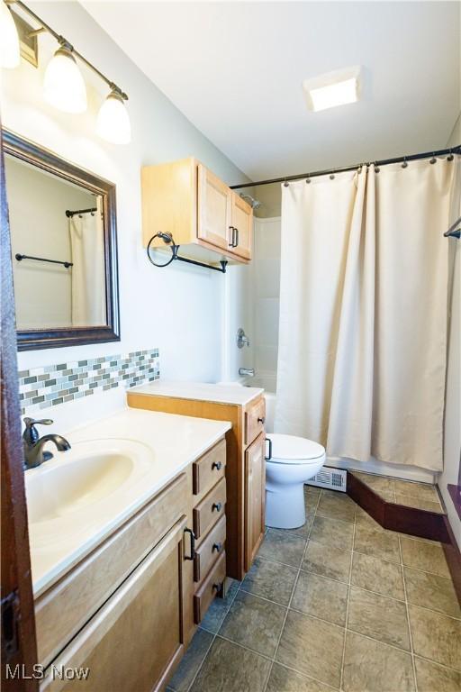 bathroom featuring backsplash, toilet, visible vents, and vanity