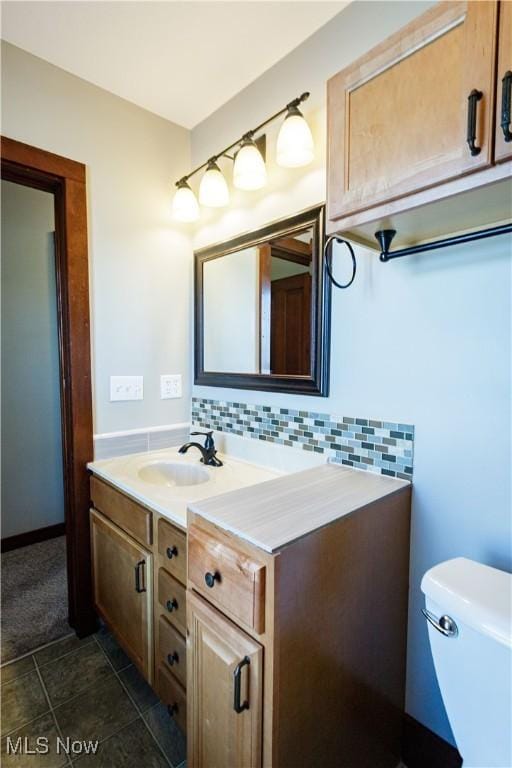 bathroom featuring vanity, backsplash, and toilet