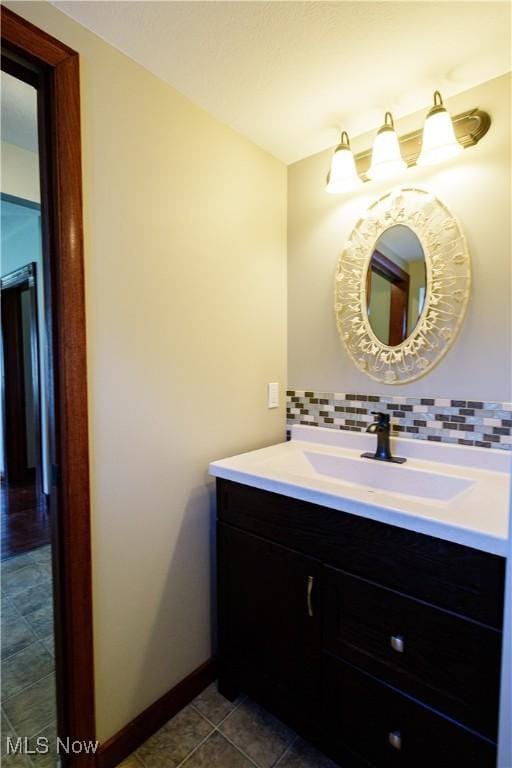 bathroom featuring vanity, baseboards, backsplash, and tile patterned floors