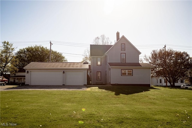 view of front of property with a detached garage, a chimney, and a front lawn