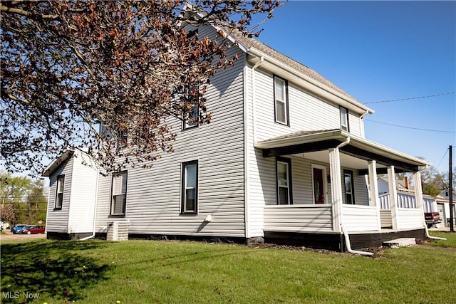view of side of home featuring a lawn and covered porch