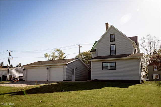 exterior space with a detached garage, a lawn, a chimney, and an outdoor structure