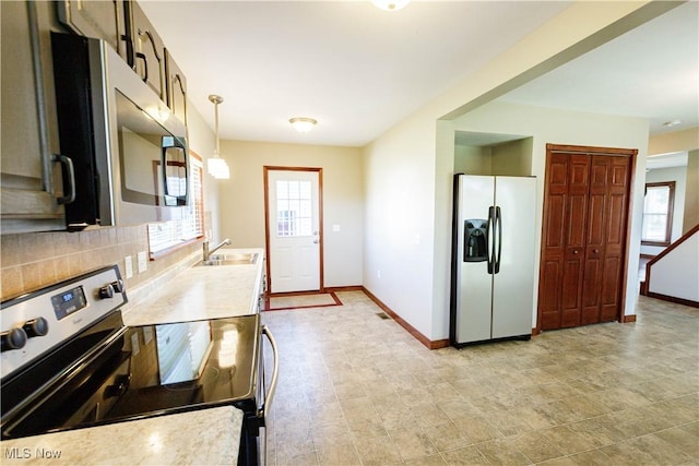 kitchen featuring baseboards, light countertops, tasteful backsplash, a sink, and stainless steel appliances