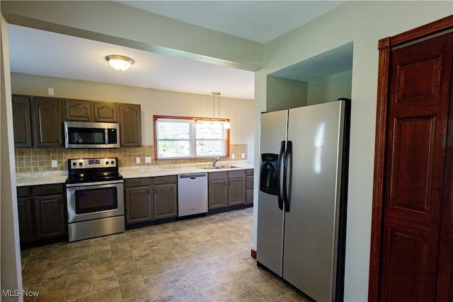 kitchen featuring light countertops, a sink, decorative backsplash, and stainless steel appliances
