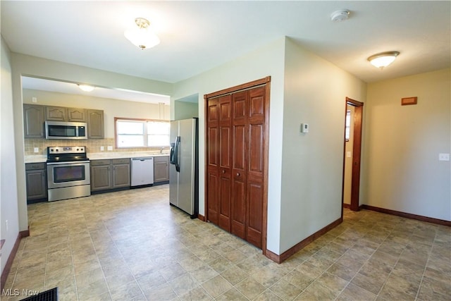 kitchen with baseboards, light countertops, gray cabinets, and appliances with stainless steel finishes