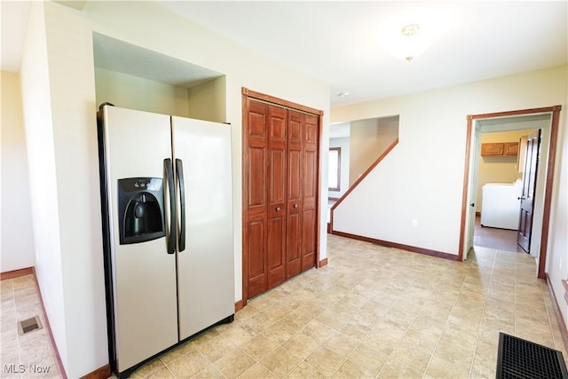 kitchen with washer / dryer, baseboards, refrigerator with ice dispenser, and visible vents