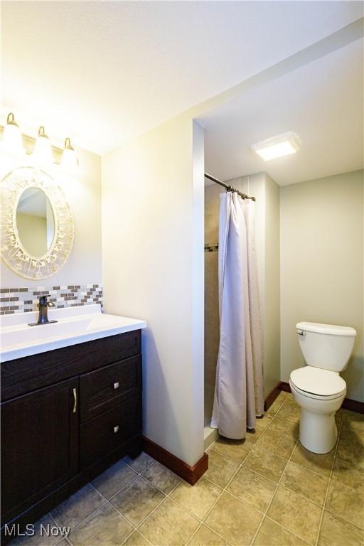 bathroom featuring vanity, decorative backsplash, toilet, baseboards, and a shower with curtain