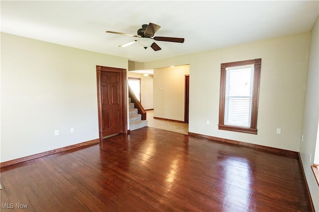 unfurnished room with stairs, ceiling fan, baseboards, and wood finished floors