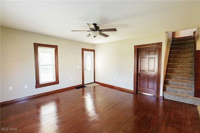 empty room featuring baseboards, ceiling fan, stairs, and wood finished floors