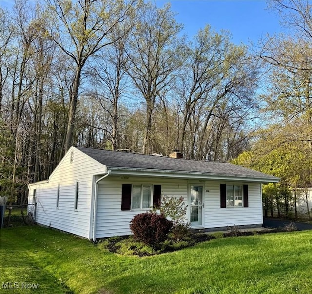 view of front of home with a shingled roof, a front lawn, fence, and a chimney