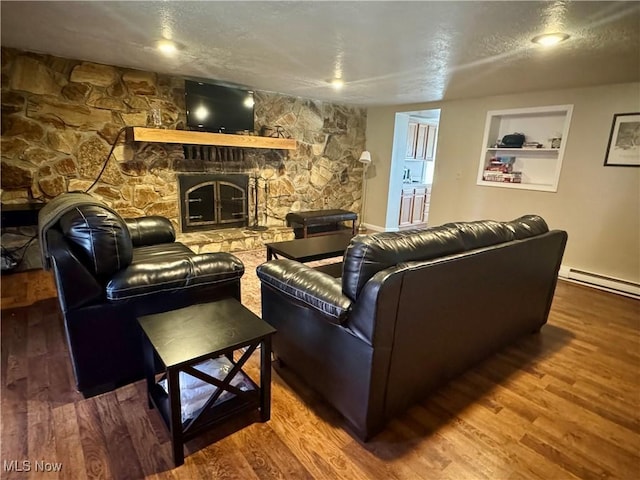 living area with a textured ceiling, a fireplace, a baseboard heating unit, and wood finished floors