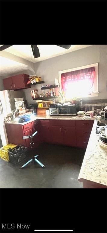 kitchen featuring light countertops, concrete flooring, ceiling fan, and stainless steel microwave