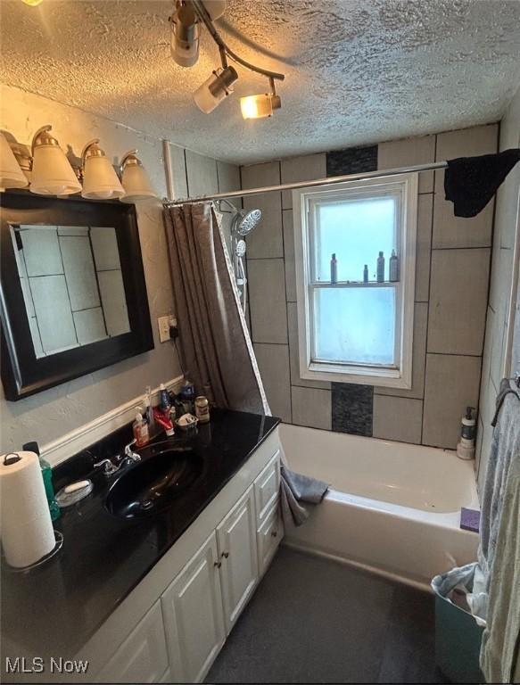 full bath featuring a textured ceiling, shower / bathtub combination with curtain, and vanity