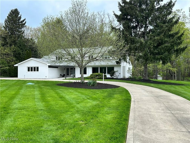 view of front of property featuring curved driveway and a front yard