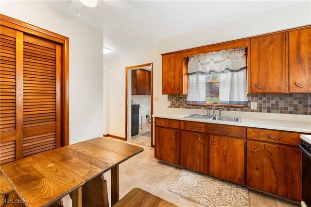 449 W Long Lake Blvd, Akron, OH 44319 - kitchen featuring a sink, light countertops, brown cabinetry, a ceiling fan, and tasteful backsplash
