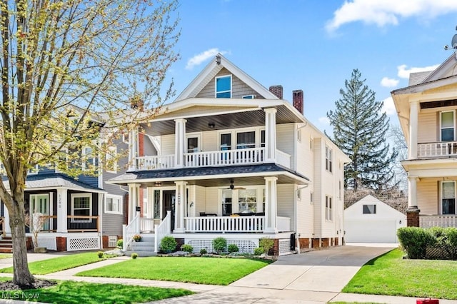 view of front of home featuring an outdoor structure, a garage, a balcony, covered porch, and a front yard