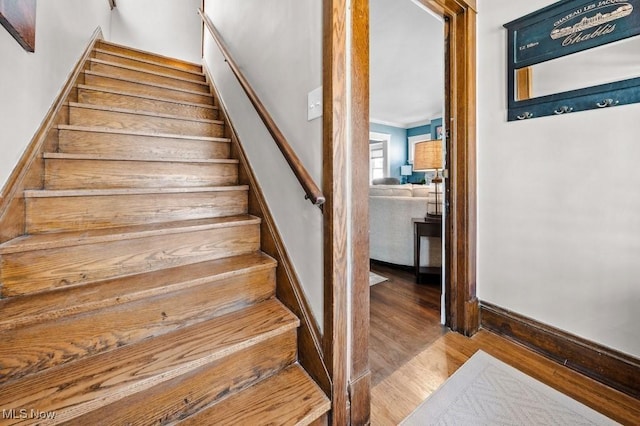 staircase featuring baseboards and wood finished floors