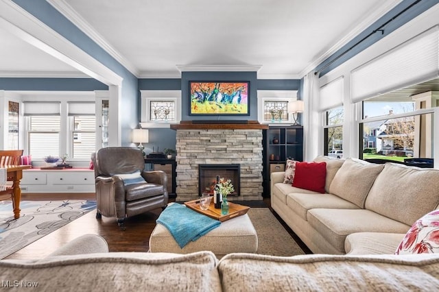 living room featuring crown molding, a stone fireplace, and wood finished floors