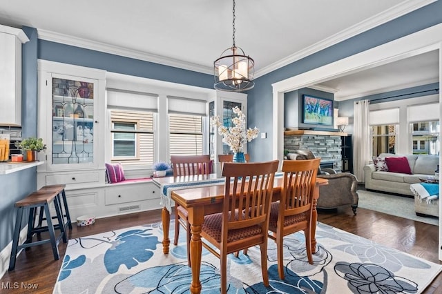 dining space with ornamental molding, a healthy amount of sunlight, and dark wood-type flooring
