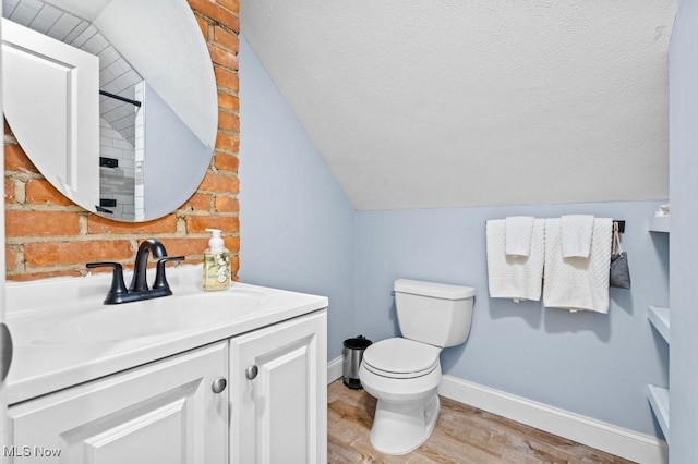 bathroom with vanity, toilet, baseboards, wood finished floors, and lofted ceiling