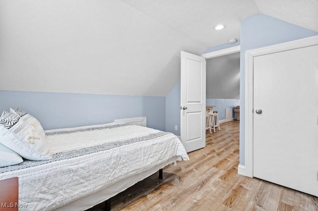 bedroom featuring recessed lighting, wood finished floors, and lofted ceiling