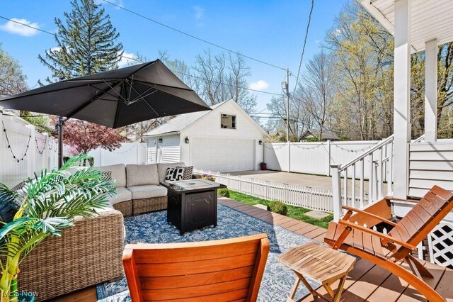 view of patio with a detached garage, an outdoor living space with a fire pit, an outdoor structure, and a fenced backyard