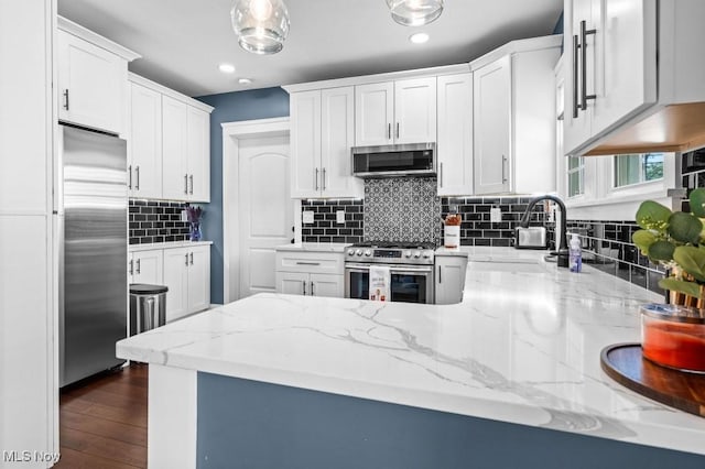 kitchen featuring a sink, light stone counters, stainless steel appliances, and white cabinetry