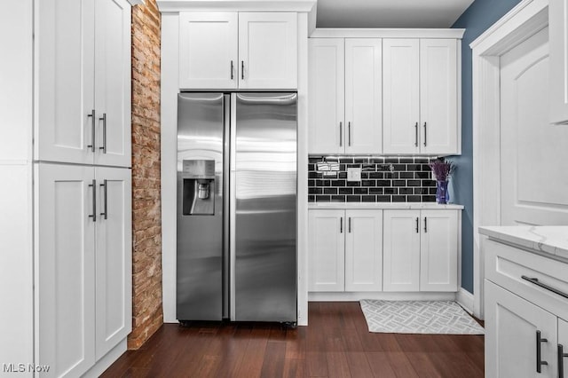 kitchen with decorative backsplash, dark wood-style flooring, stainless steel fridge, white cabinets, and light stone counters