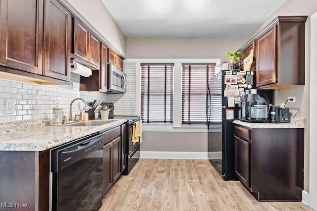 kitchen featuring a sink, light wood finished floors, light countertops, baseboards, and black appliances