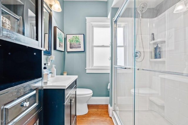 full bathroom featuring vanity, toilet, baseboards, a shower stall, and wood finished floors