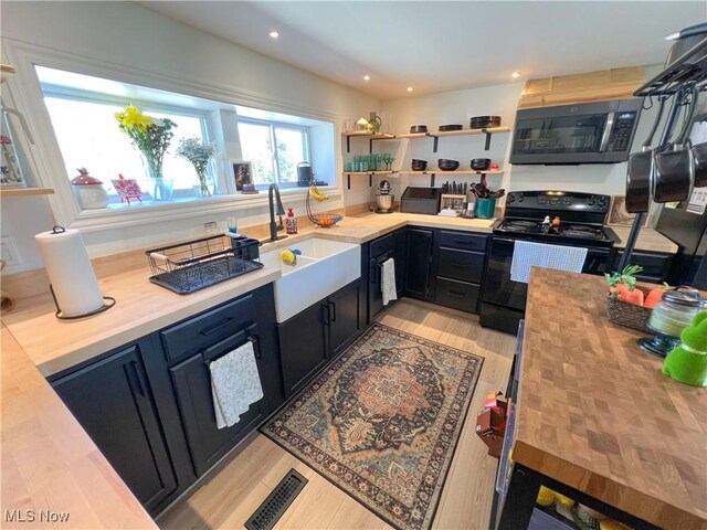 kitchen with electric range, open shelves, dark cabinets, wooden counters, and visible vents