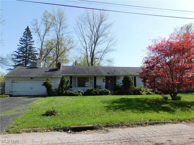 ranch-style home with a garage, a chimney, a front yard, and aphalt driveway