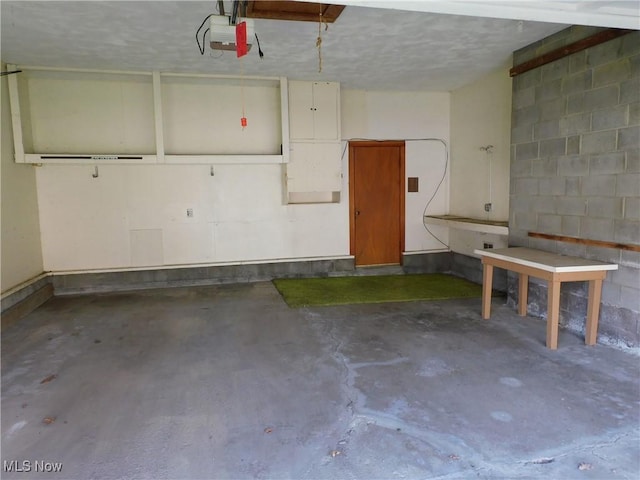 garage with a garage door opener and concrete block wall