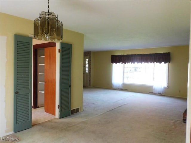 carpeted spare room with baseboards and a chandelier