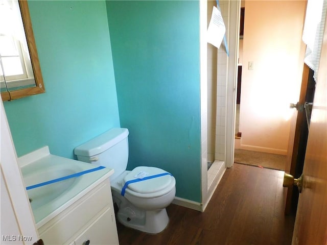 full bath featuring a shower stall, wood finished floors, vanity, baseboards, and toilet