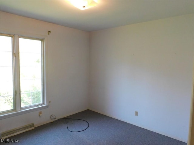 spare room featuring carpet floors and a baseboard heating unit
