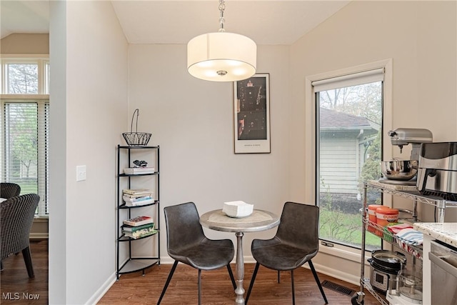 dining area with baseboards, lofted ceiling, wood finished floors, and visible vents