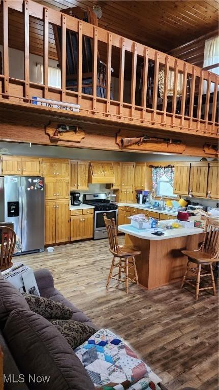 kitchen with a peninsula, a kitchen bar, light countertops, light wood-style flooring, and appliances with stainless steel finishes