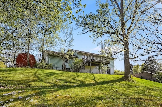 rear view of house featuring a yard, a deck, and an outbuilding