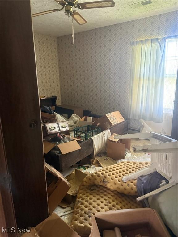 bedroom with ceiling fan and wallpapered walls