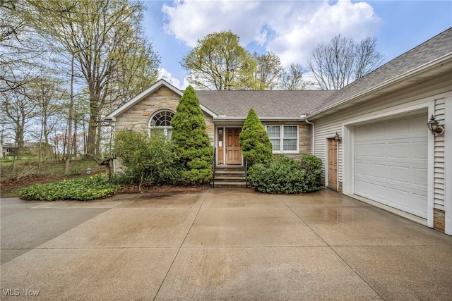 ranch-style home featuring a garage, a shingled roof, stone siding, and concrete driveway