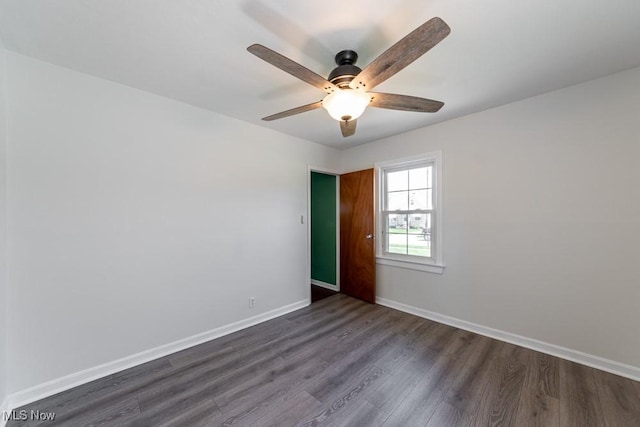 spare room featuring baseboards, a ceiling fan, and dark wood-style floors