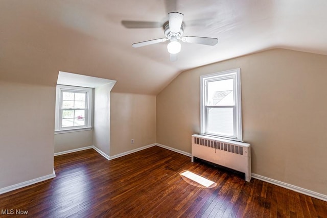 bonus room with wood-type flooring, lofted ceiling, baseboards, radiator heating unit, and a ceiling fan