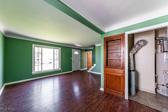 foyer with gas water heater, a textured ceiling, stairs, baseboards, and wood finished floors