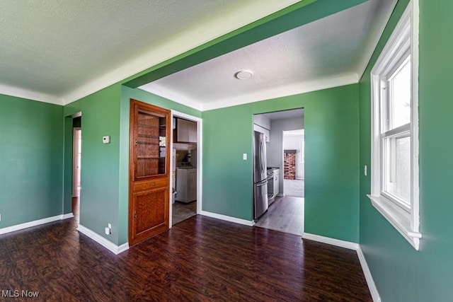 spare room featuring baseboards, wood finished floors, and a wealth of natural light