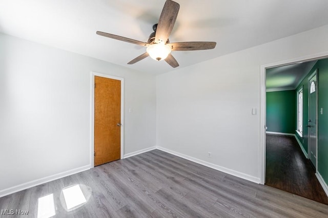 unfurnished room with baseboards, a ceiling fan, and wood finished floors