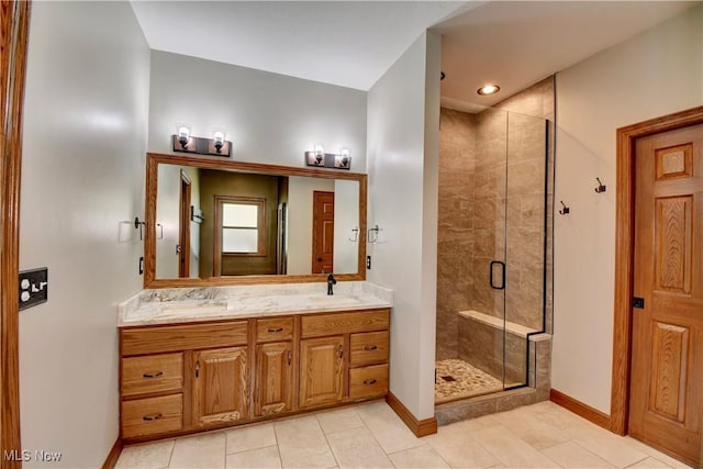 full bath with a sink, baseboards, a shower stall, and double vanity