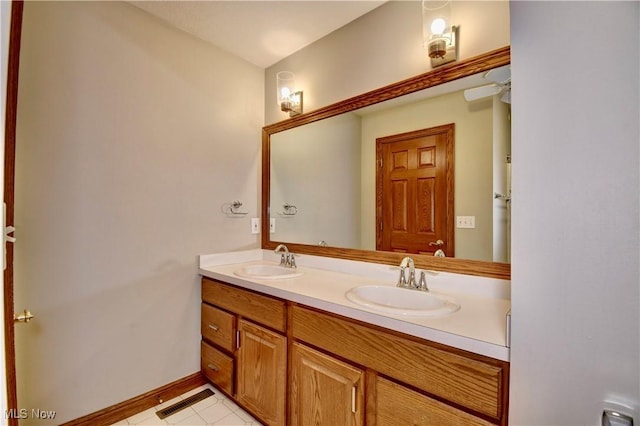 full bath featuring double vanity, a sink, baseboards, and visible vents